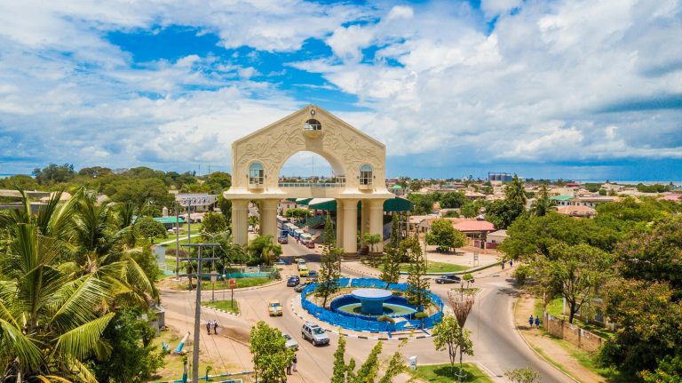 Scenic aerial view of Arch 22 in Banjul, The Gambia amid lush greenery and cloudy sky.